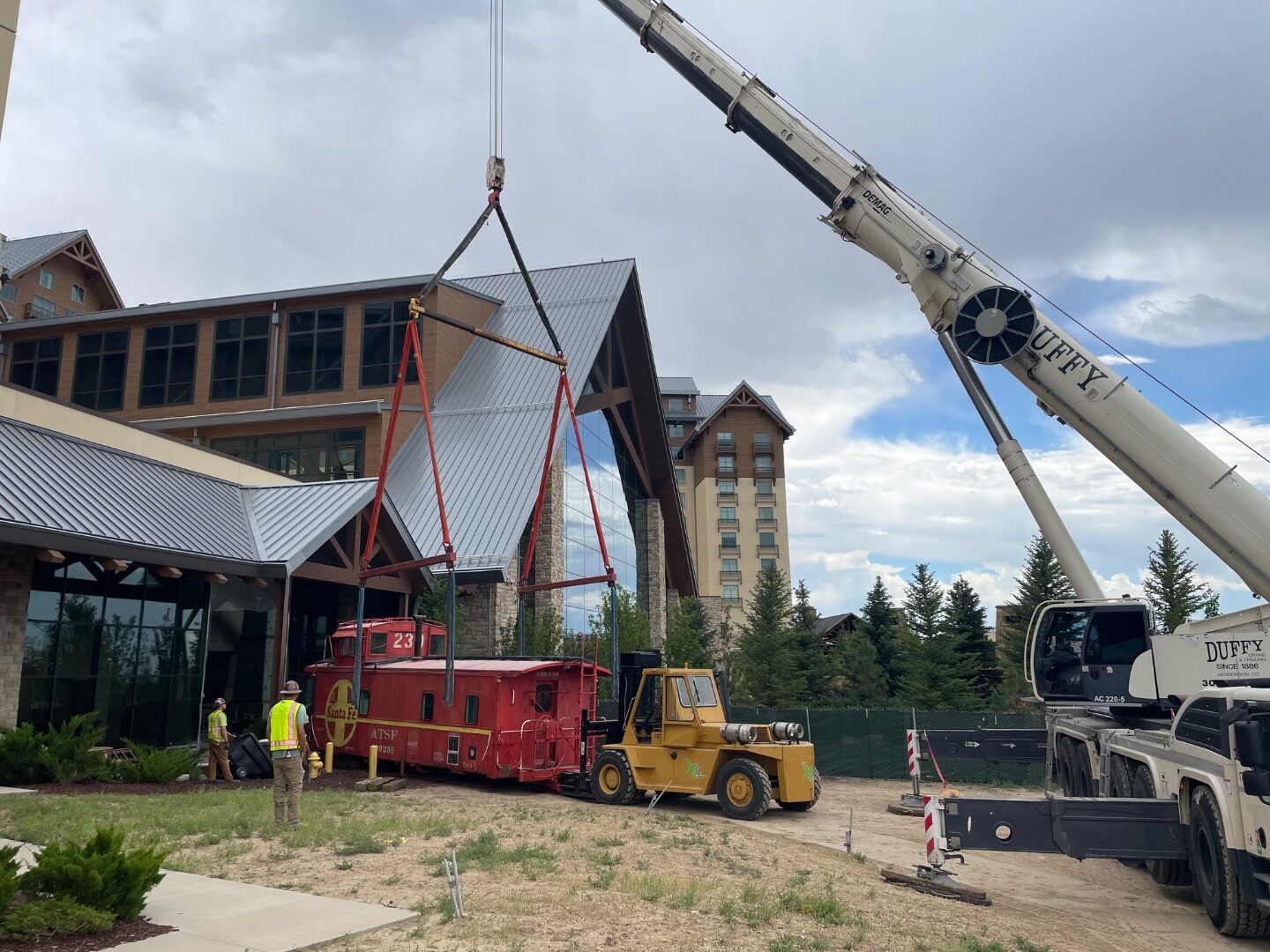 Mobile crane placing a vintage caboose