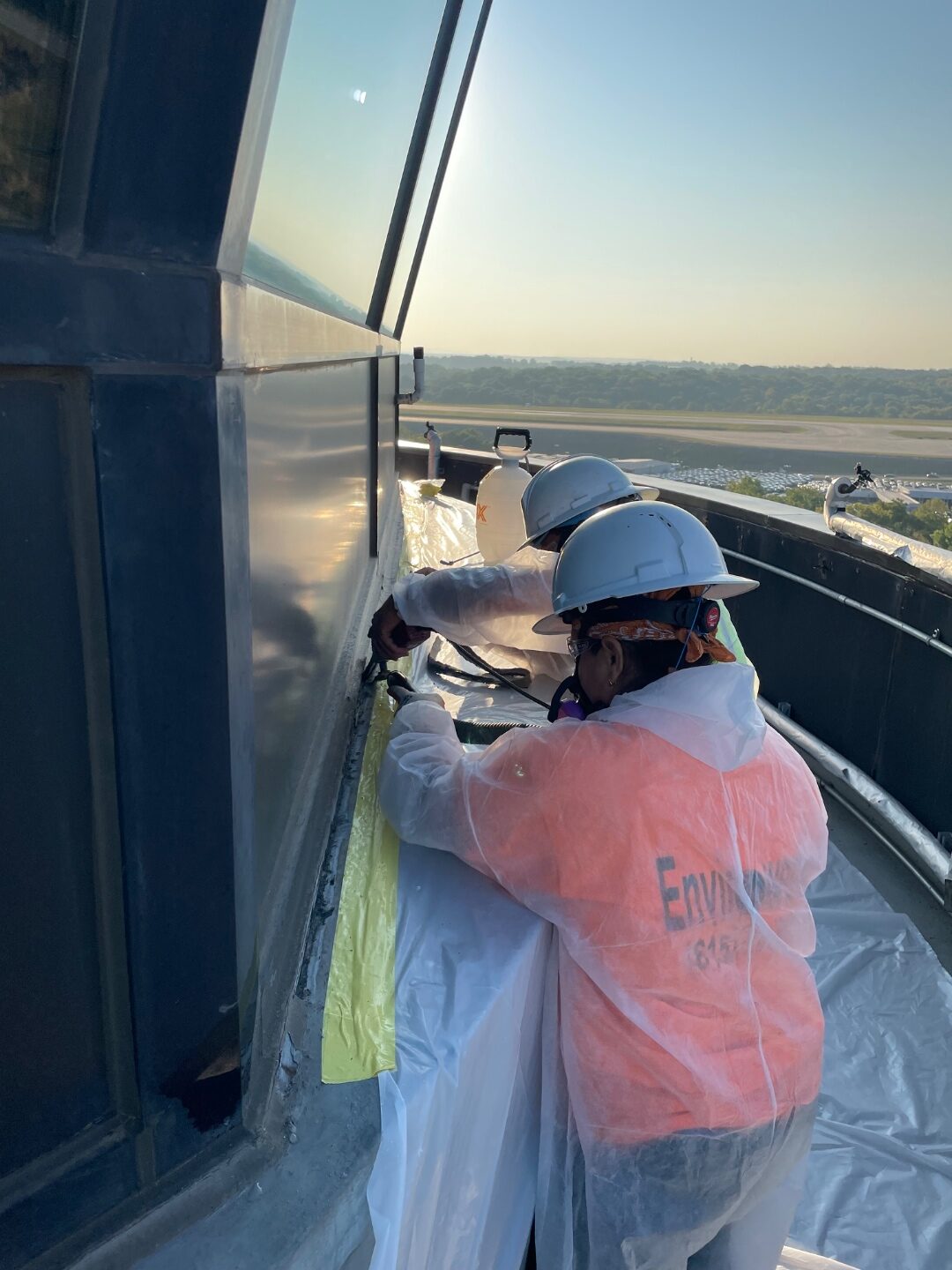Technicians in protective suits working a high-rise ledge