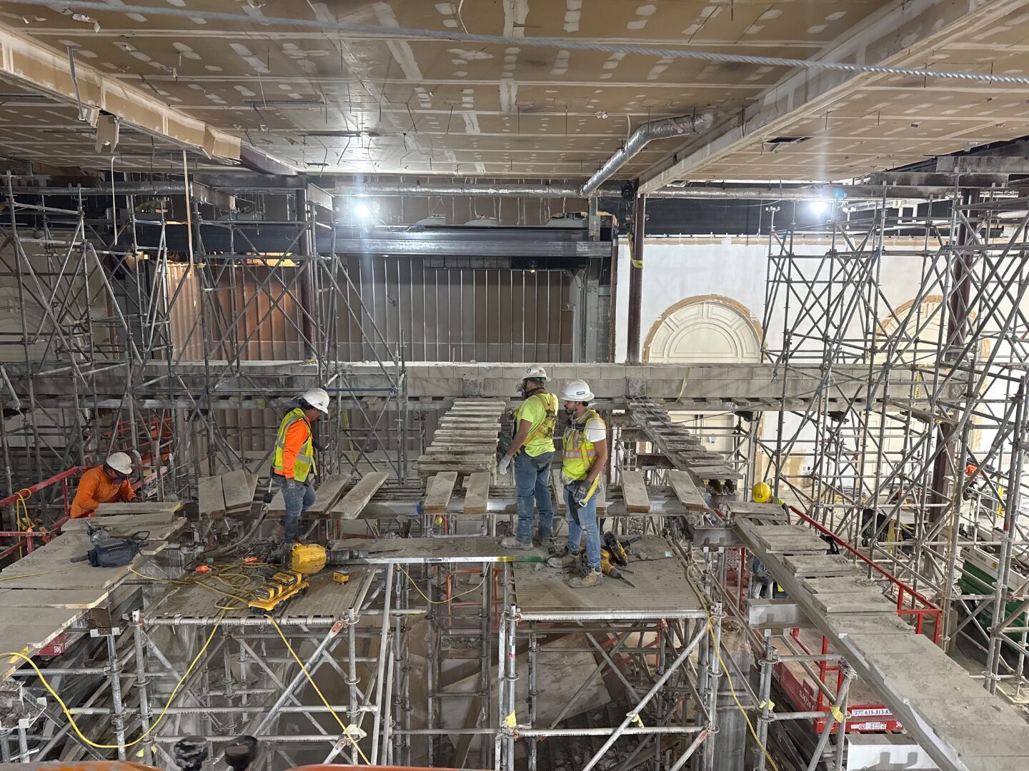 Workers performing structural demolition from scaffolding